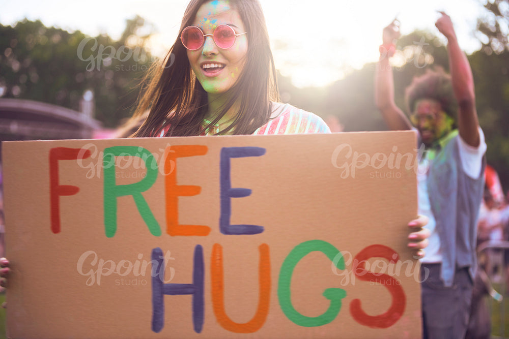 Happy woman holding banner "free hugs" during summer music festival