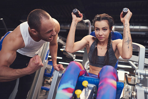 Personal trainer guding young woman at gym