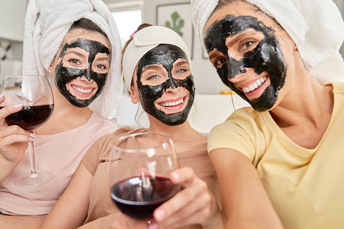 Three smiling friends taking selfies with face masks on faces