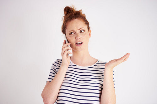 Amazed woman talking by mobile phone at studio shot