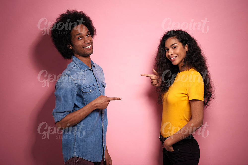Young African couple pointing a finger at each other.