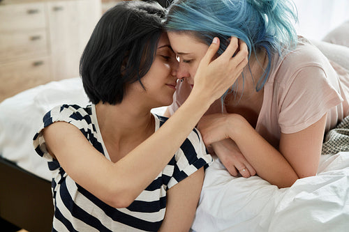 Romantic lesbian couple kissing lovingly in the bedroom