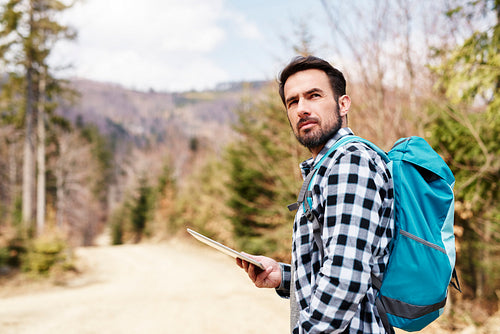 Hiking man with backpack and tablet enjoying at view