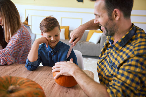 Father helping son in carving pumpkins