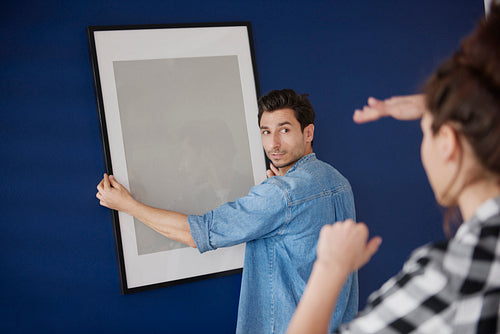 Couple hanging a picture frame on the blue wall