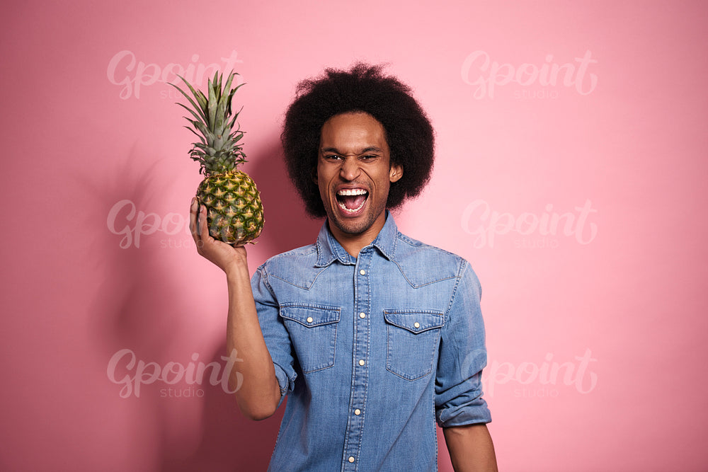 Happiness African man holding a pineapple in a studio shot.
