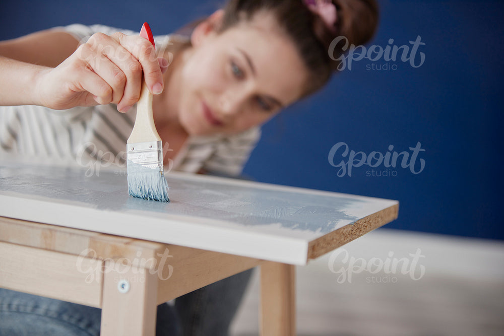 Close up of young woman repainting old furniture