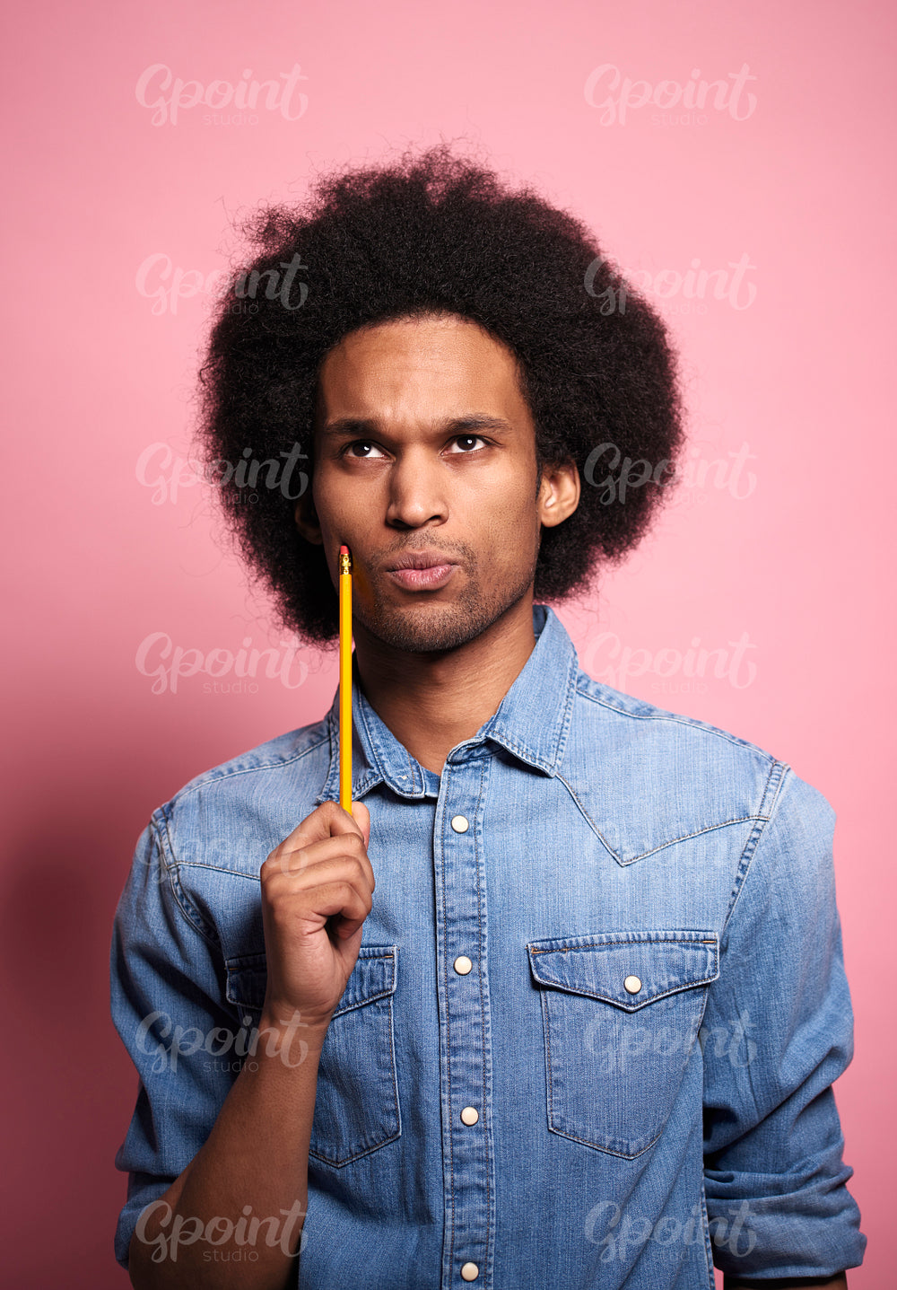 Young African man thinking something with a pencil in hand.