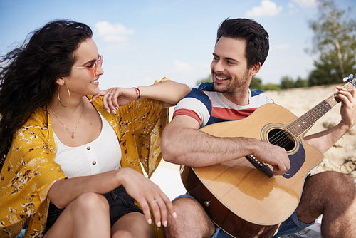 Happy man playing guitar for beautiful woman