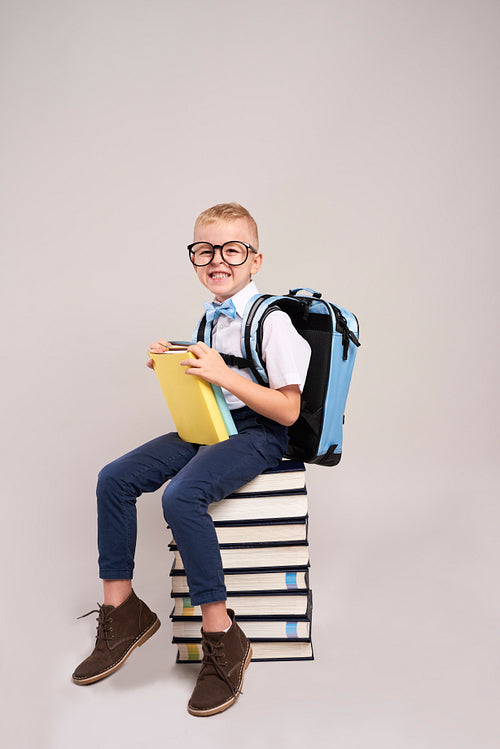Happy child with backpack and stack of books