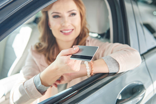 Woman sitting in a car with credit card