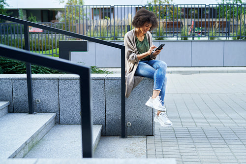 Woman sitting on city steps and scrolling on the phone