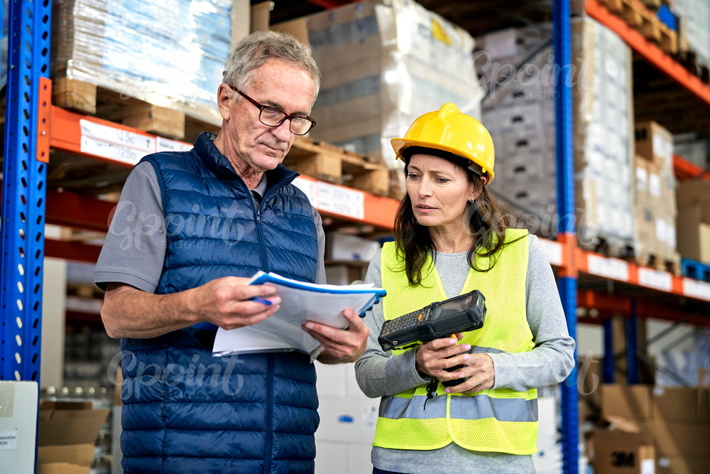 Two caucasian workers in mature age discussing together in warehouse 