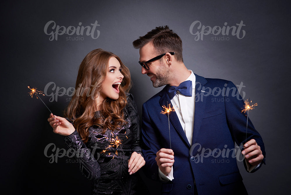 Cheerful couple with sparkler flirting