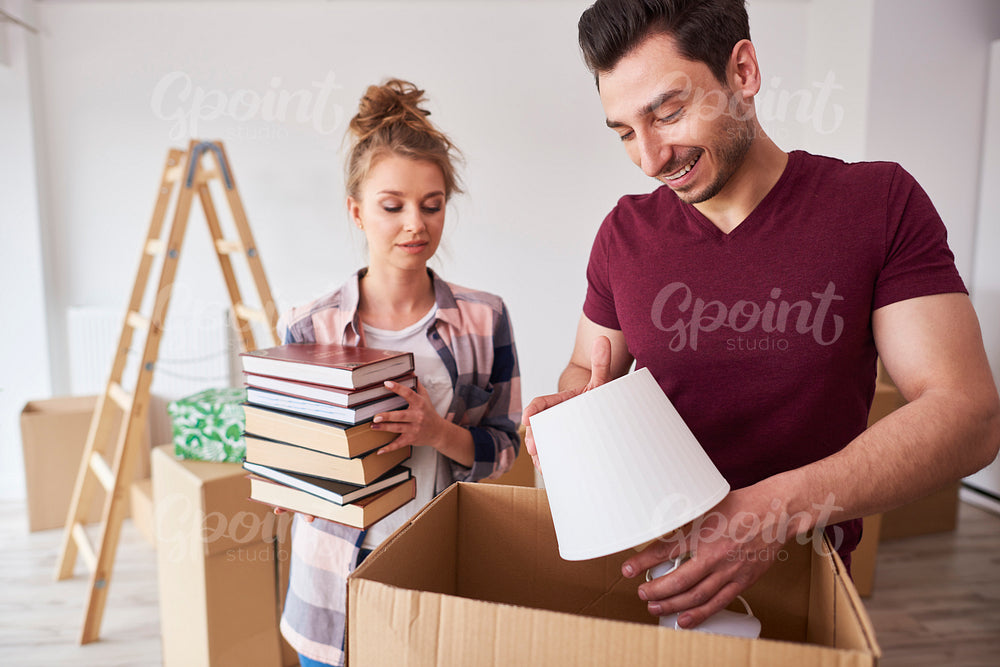 Couple packing books and lamp to the boxes
