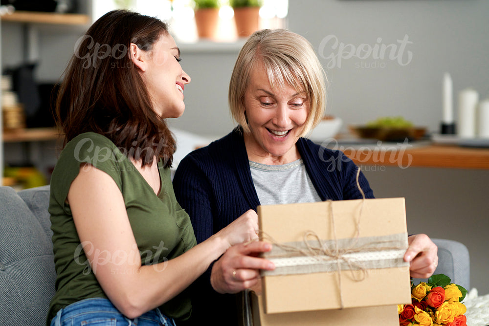 Happy mother unwrapping a gift from her adult daughter