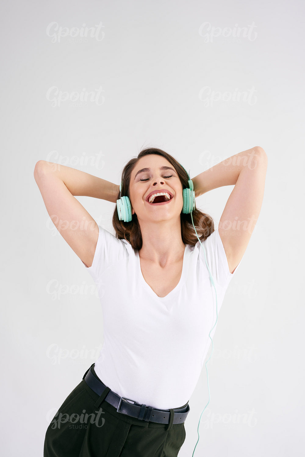 Joyful woman with headphones listening to music in studio shot