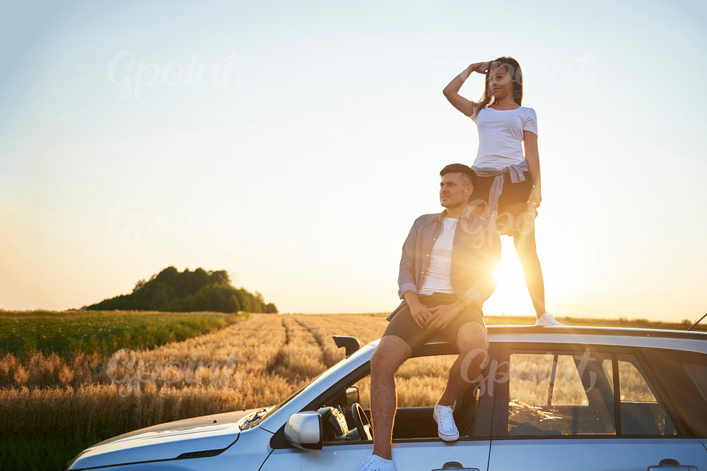 Young couple sitting on car