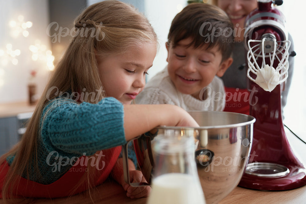 Siblings tasting sugar paste during baking with family