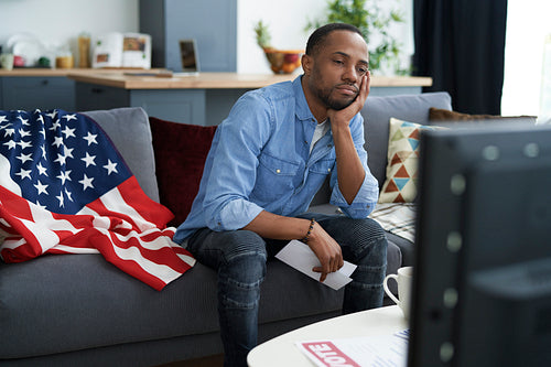 Bored man watching TV with information about election