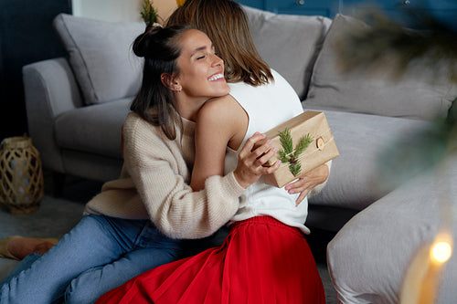 Two female friends hugging and exchanging gifts