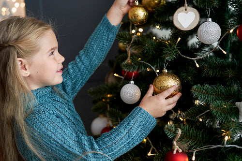 Cute girl hanging decorations on Christmas tree