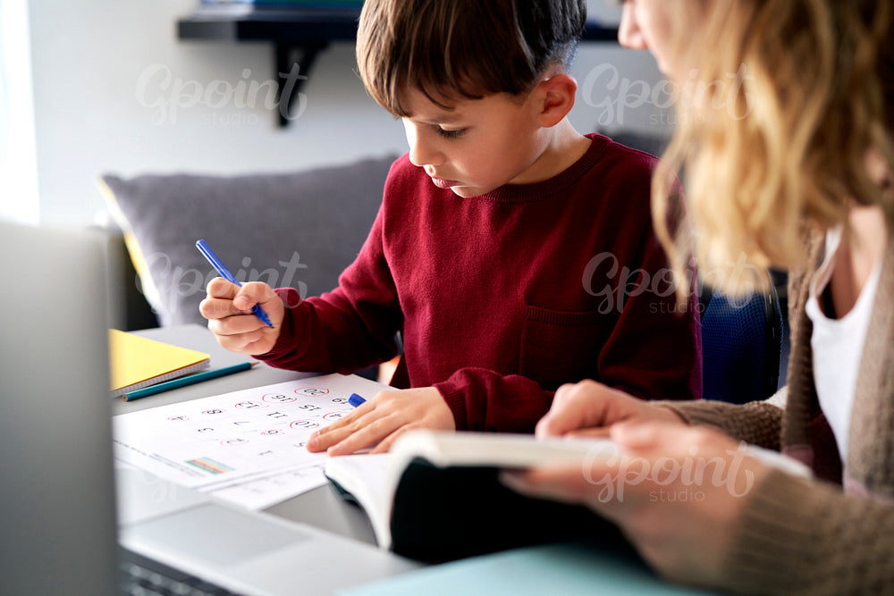 Boy with the help of his mother doing his homework