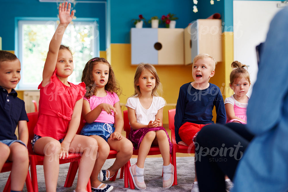 Girl raising her hand to ask question in classroom