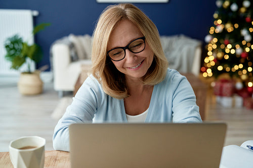 Front view of mature woman using laptop during Christmas time