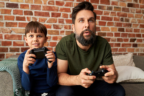 Focused father and son playing video game together