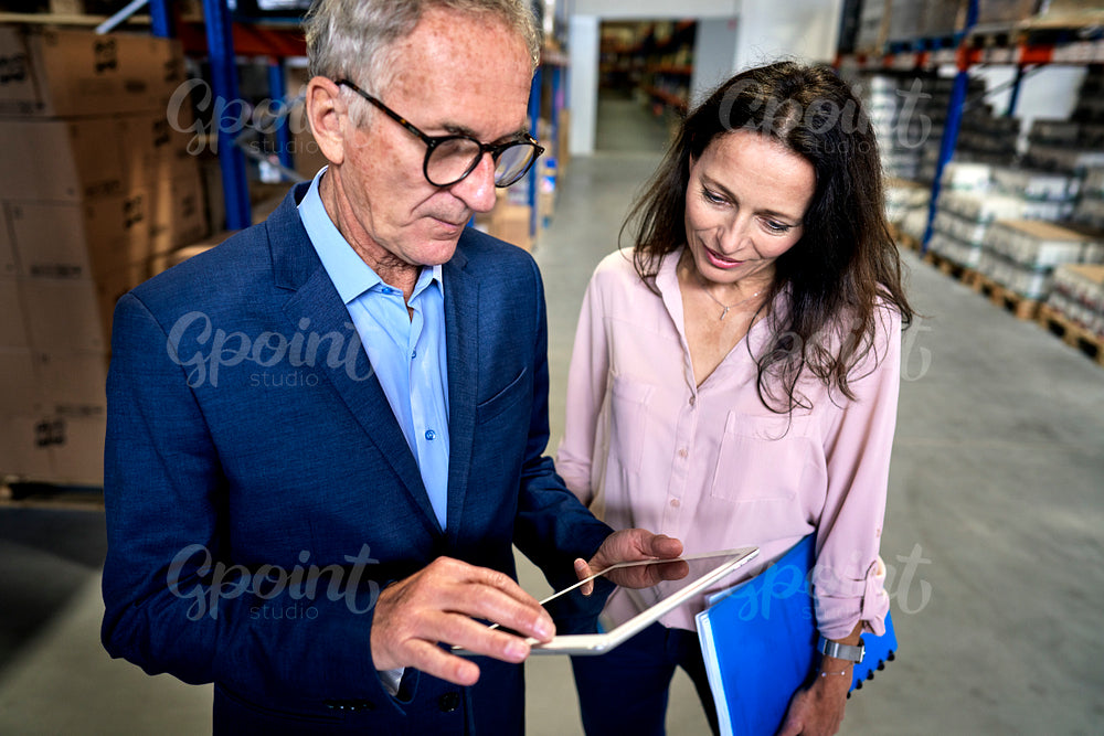 Caucasian mature man and woman discussing in a warehouse