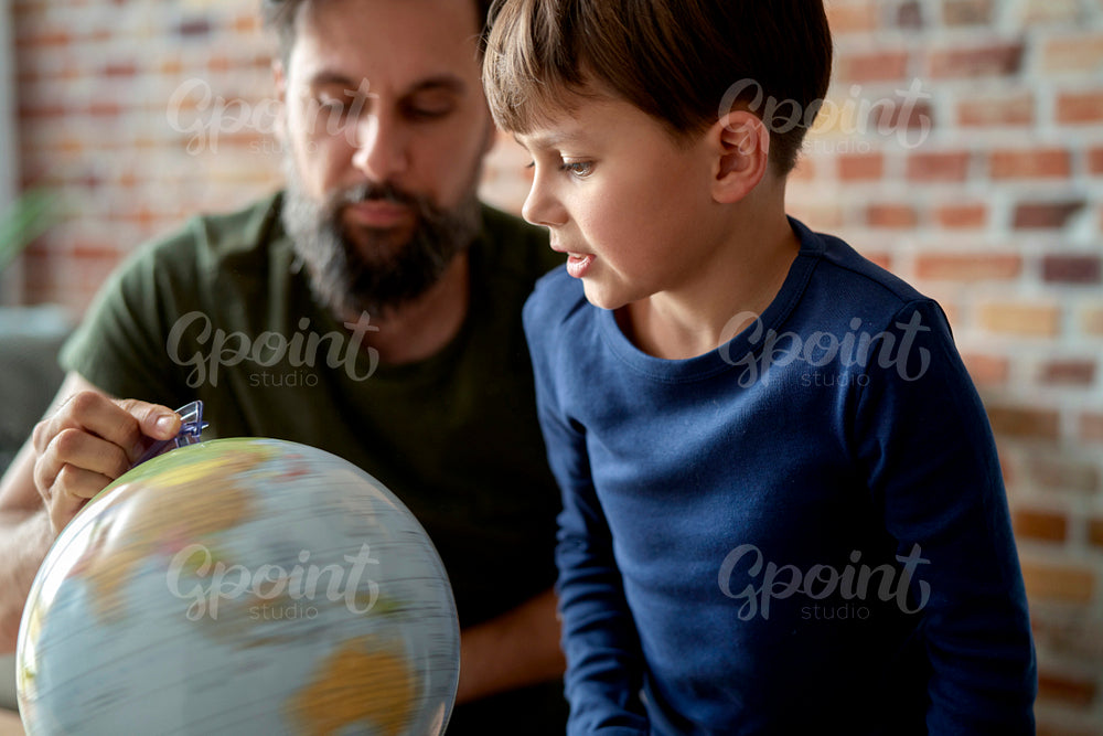 Son and father looking at spinning globe