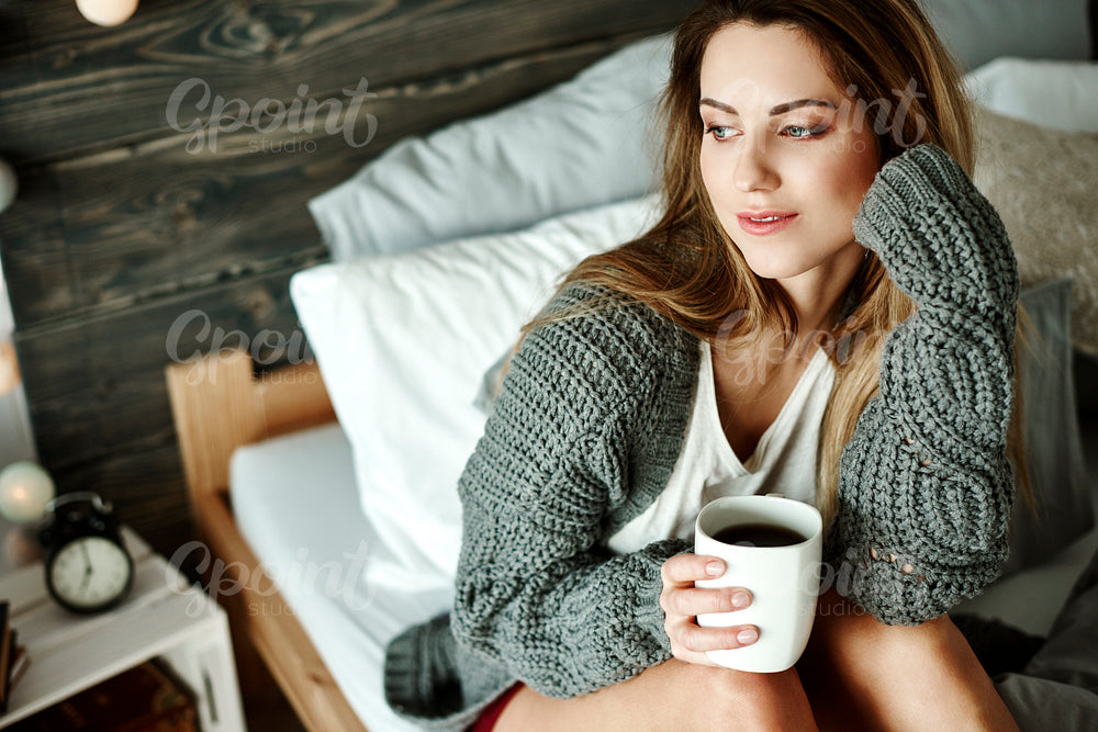 Thoughtful woman with coffee looking through window