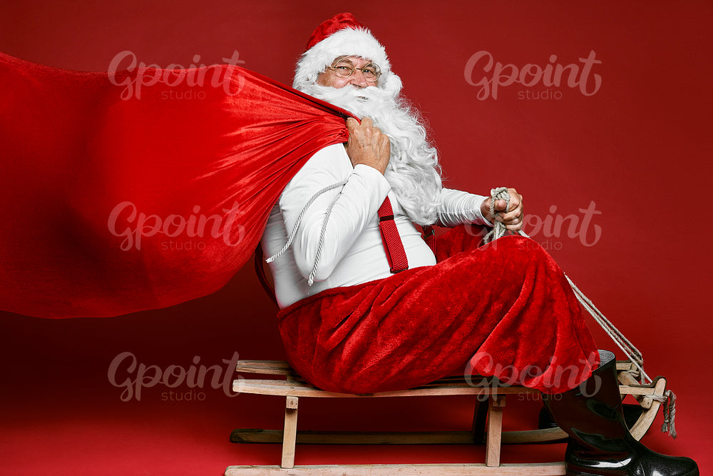Caucasian Santa Claus with sack of Christmas Presents go of sledge