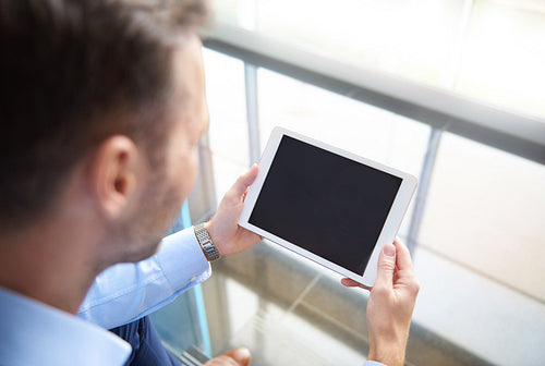 Rear view of man browsing digital tablet