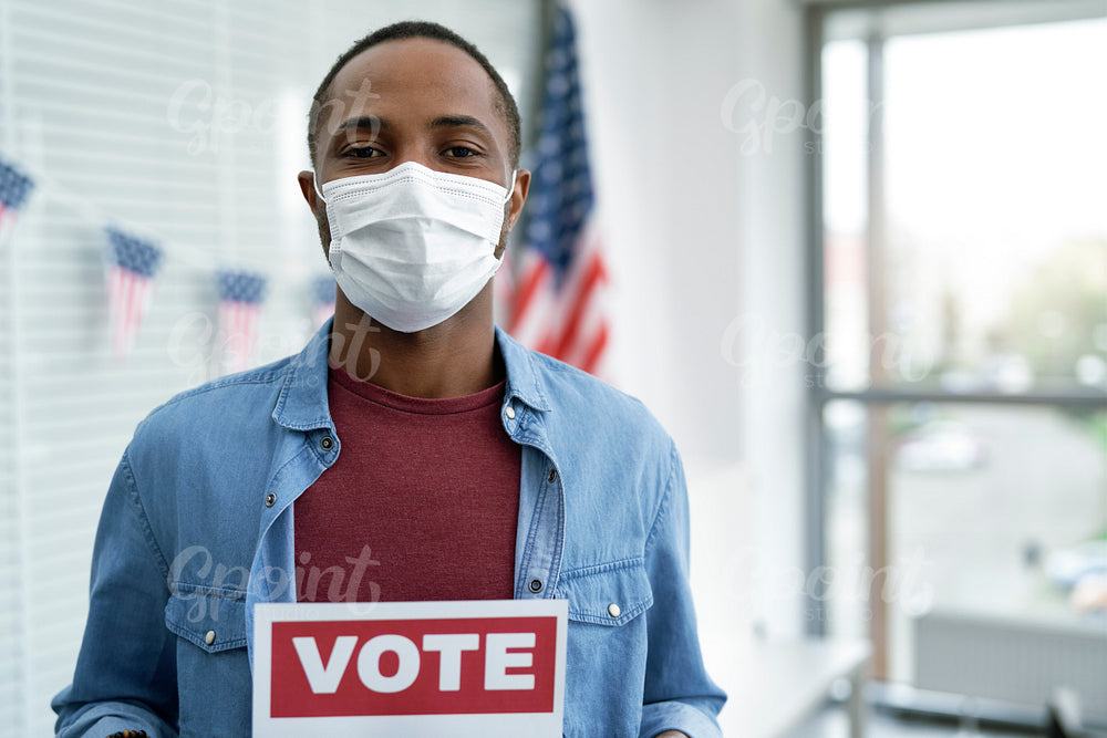 Black man in face mask with voting card