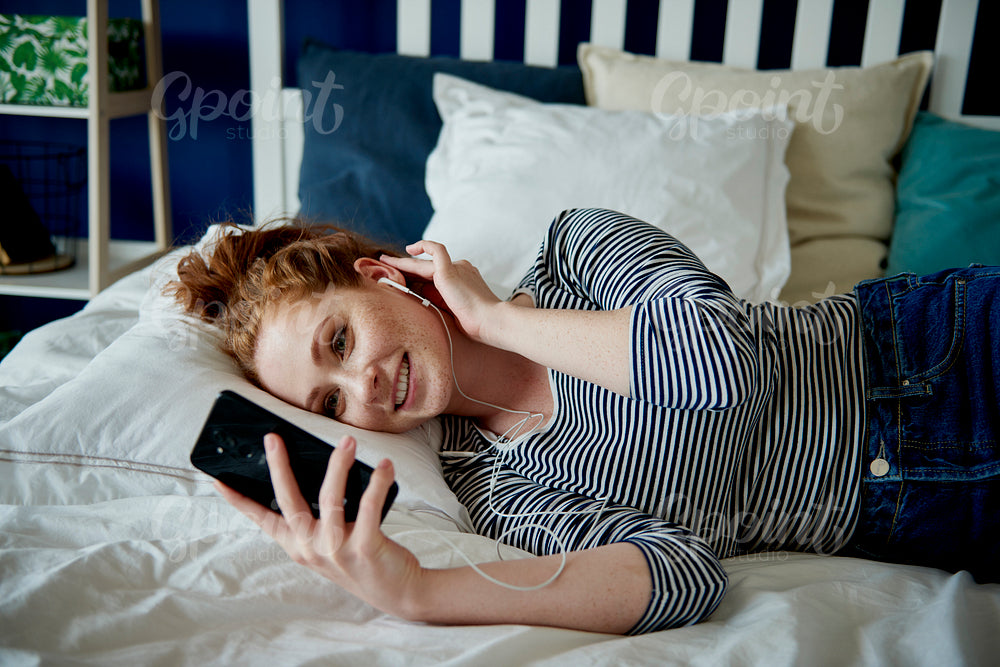 Redhead woman having a videoconference in her bed