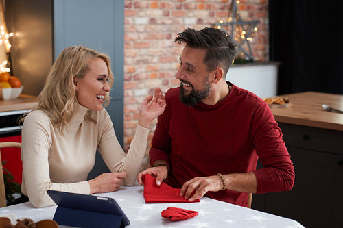Happy couple folding Christmas napkins on the table