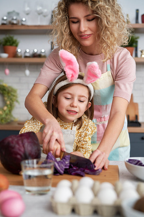 Mom and daughter cutting red cabbage to color the eggs