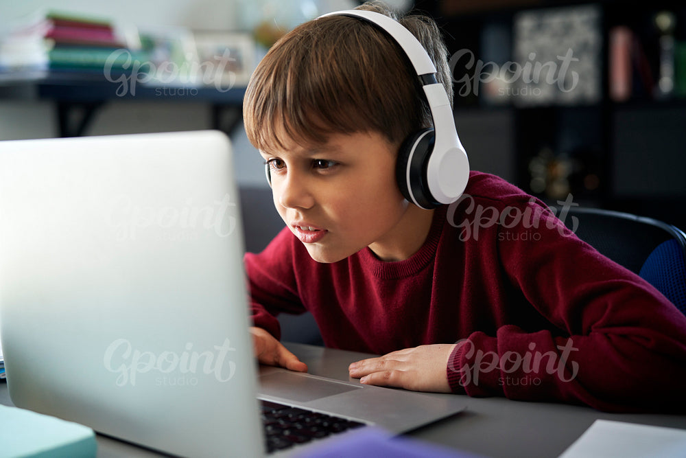 Concentrated boy in headphones in front of laptop