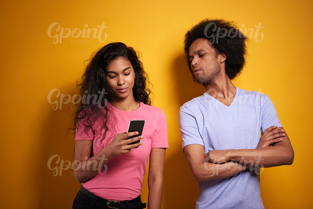Jealous man peeking at phone of his girlfriend