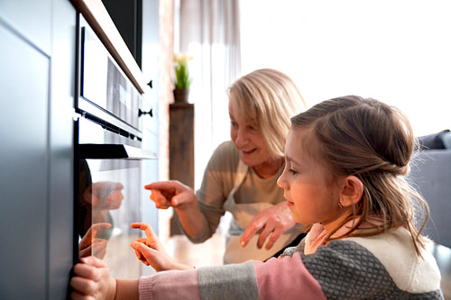 Grandma with her granddaughter watching Easter biscuits in kitchen oven