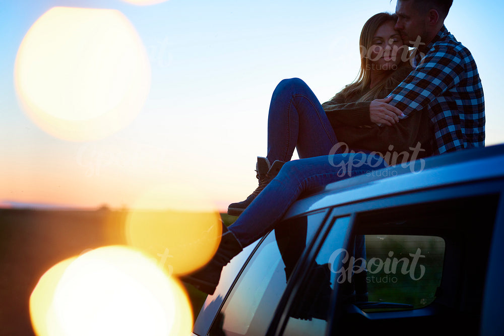 Loving couple embracing and sitting on car