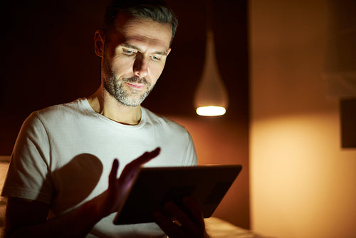Focused man using tablet at night