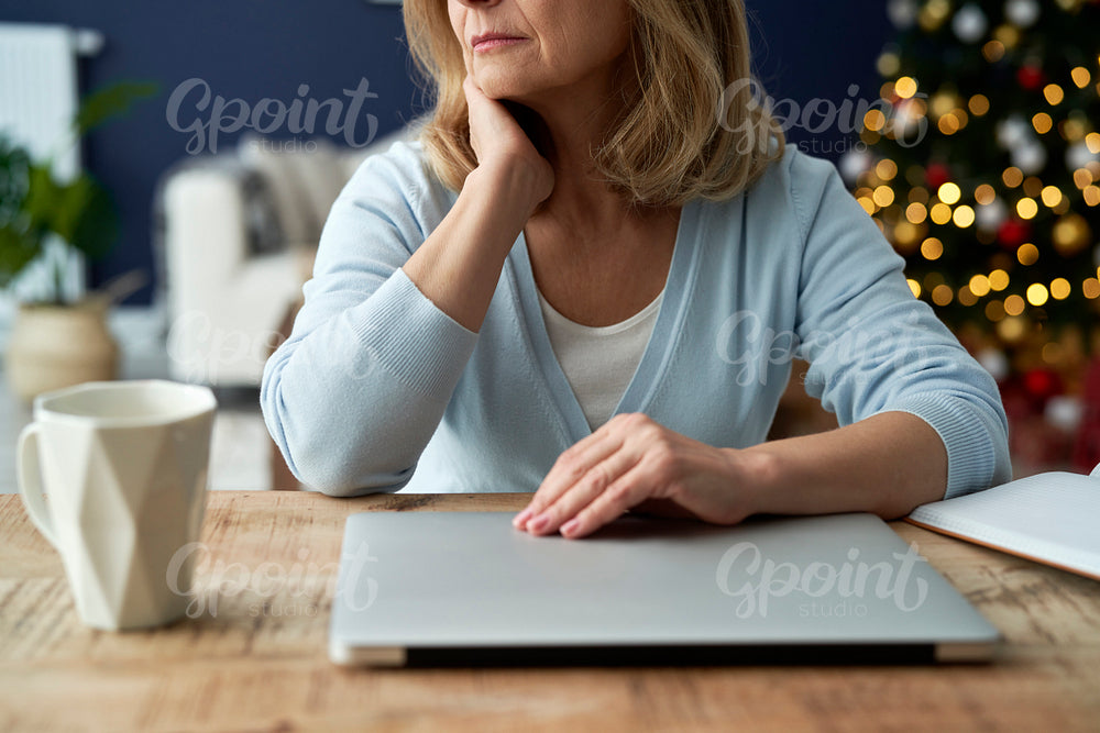 Mature woman sitting at table with laptop in Christmas time