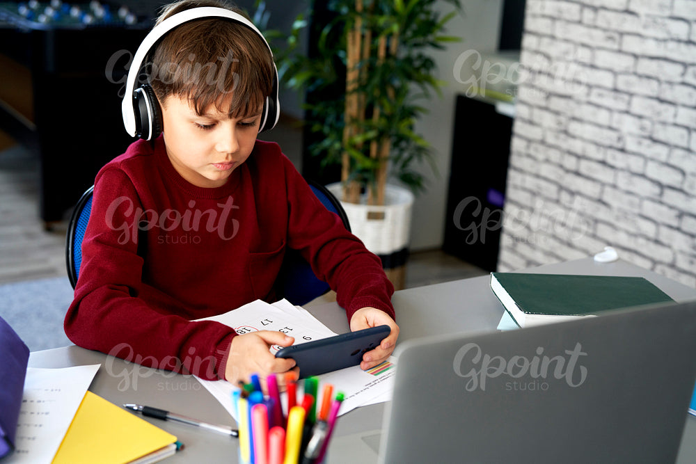 Schoolboy playing on the phone during homeschooling