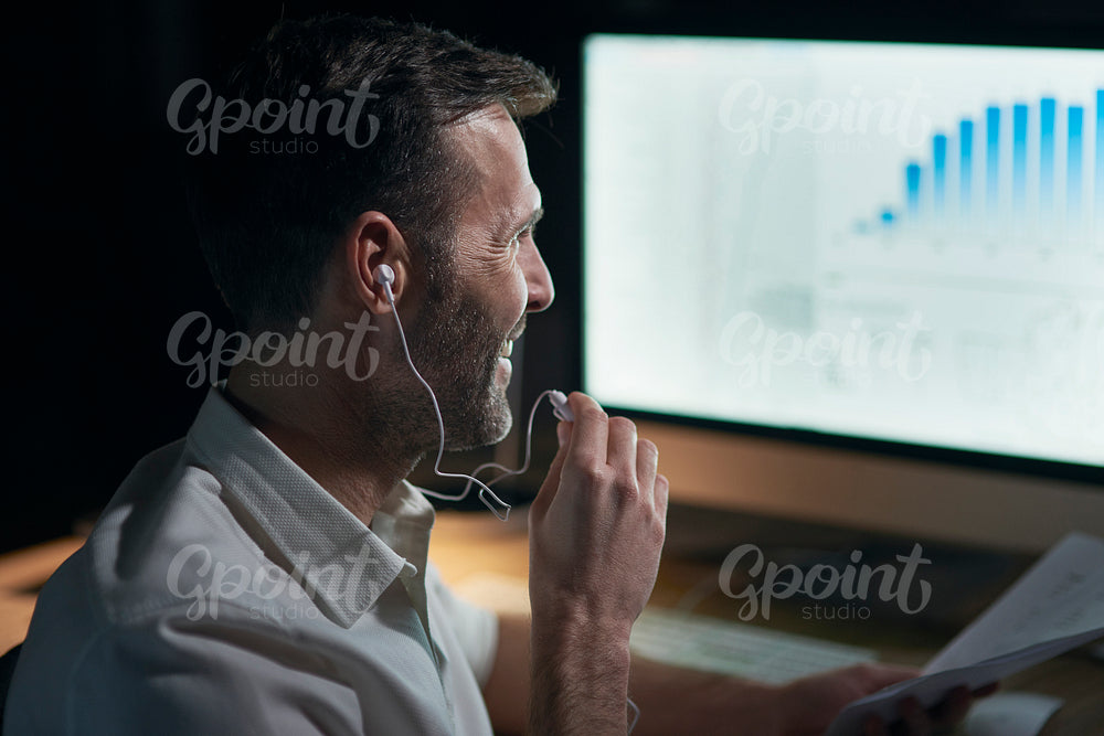 Side view of man listening to music in his office