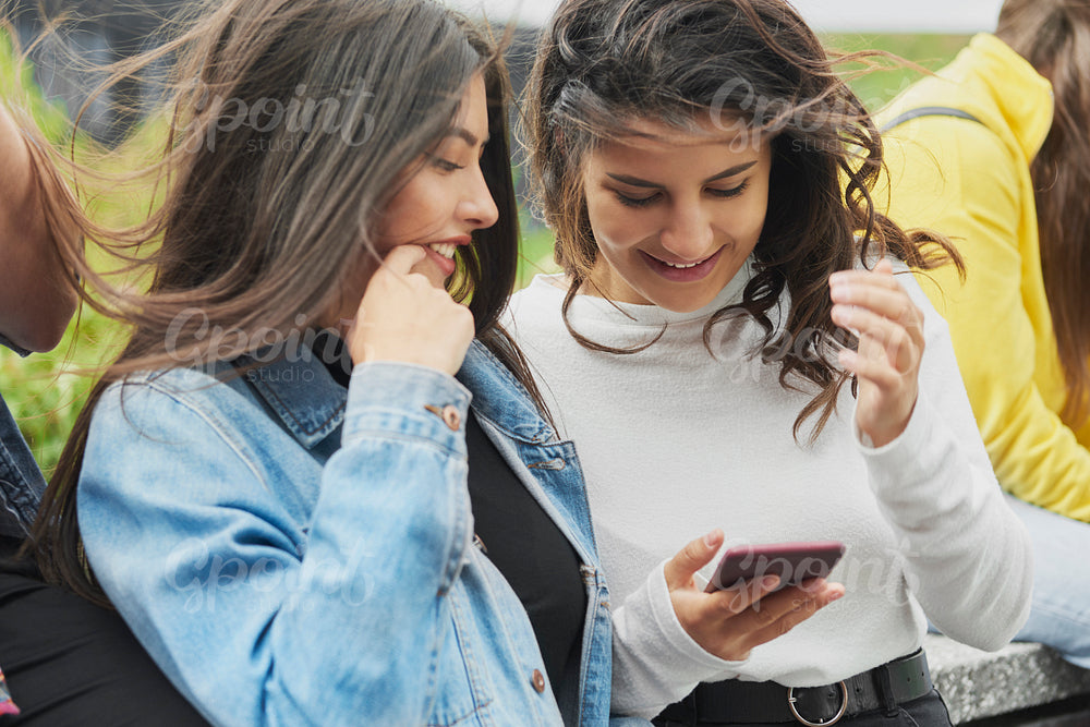 Two young women using mobile phone outdoors