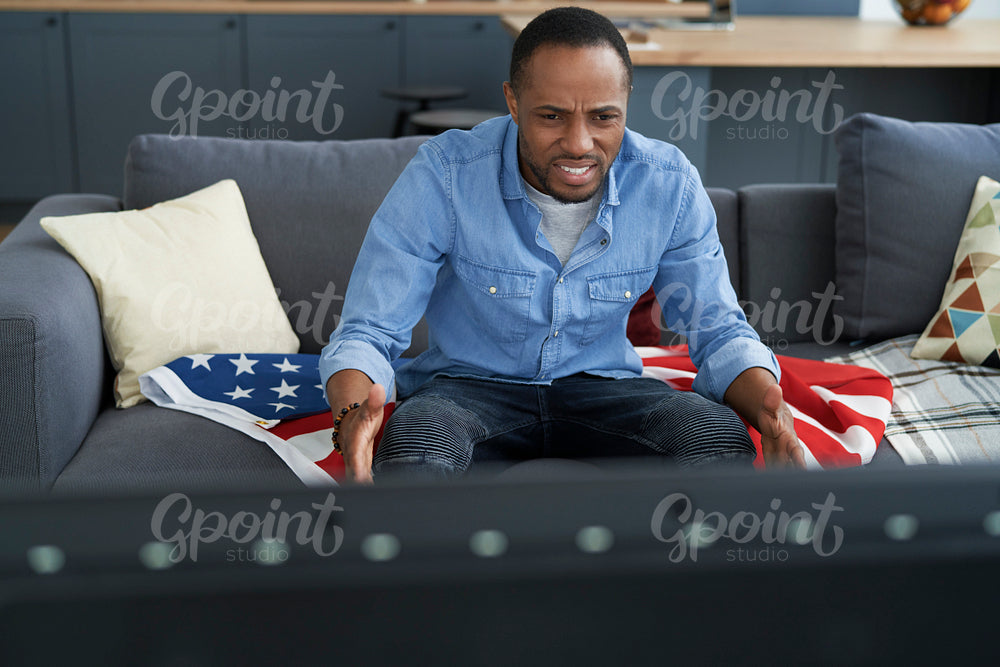 High angle view of frustrated man watching TV