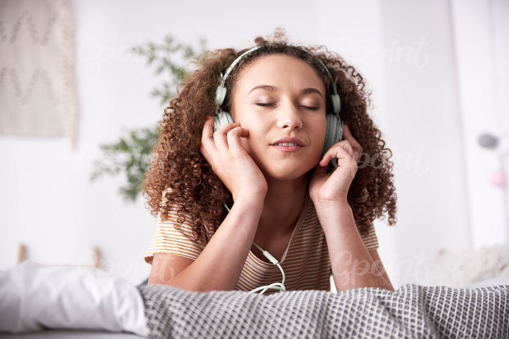 Young woman listening to music on the bed